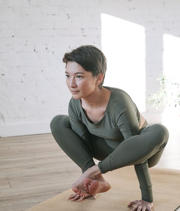Woman performing a yoga pose in a bright and calm room.